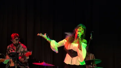 La misma cantante de blusa blanca girando sobre sí misma, con el brazo extendido.