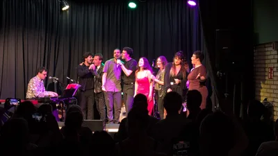 Todos los cantantes juntos en el escenario al final del concierto, con el teclista a la izquierda.