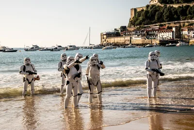 Un grupo de soldados imperiales llega a la orilla y uno señala hacia la playa; detrás, el puerto y el Aquarium.