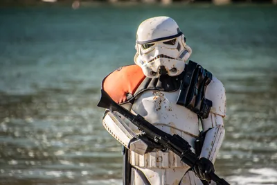 El mismo soldado imperial de hombrera naranja, con el agua de la bahía desenfocada detrás.