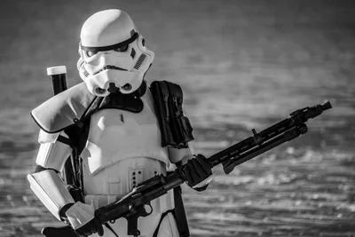 En blanco y negro, un soldado imperial con mochila y un fusil largo, con el mar de fondo.