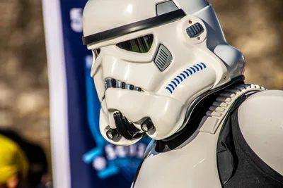 Casco de soldado imperial de perfil, con una bandera azul de la Legión 501 detrás.