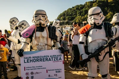Dos soldados imperiales sostienen el cartel en euskera «Haur-minbiziaren aurkako lehorreratzea», el del desembarco a favor de Aspanogi, rodeados de gente.