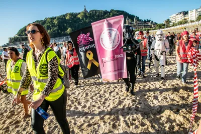 Una voluntaria de chaleco amarillo abre paso a las banderas de Aspanogi y The Pink Force, un piloto TIE y un soldado imperial.