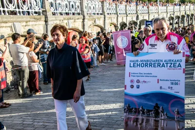 Por el paseo, junto a la barandilla de La Concha, un voluntario lleva el cartel bilingüe del desembarco.