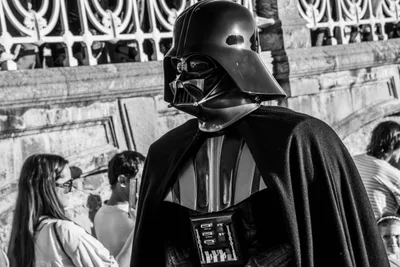 En blanco y negro, Darth Vader pasa delante de los arcos de la barandilla de La Concha, entre el público.