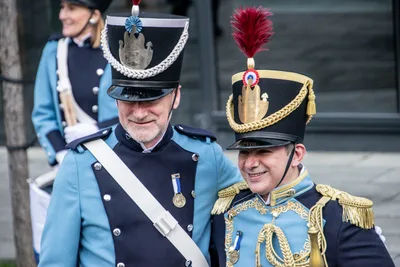 Dos tamborreros sonríen juntos: un soldado de azul celeste y el tambor mayor, con penacho rojo y charreteras doradas.