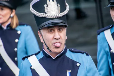 Un soldado con chacó negro y galón plateado saca la lengua a la cámara.