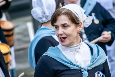 Una aguadora con cofia blanca y toquilla azul celeste habla con alguien fuera de la foto.