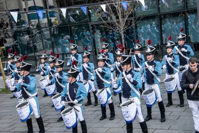 Las filas de soldados de azul celeste tocan sus tambores blancos con flecos azules.