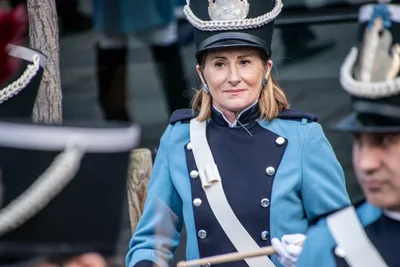 Una tamborrera de azul celeste con chacó sonríe de pie en la formación.
