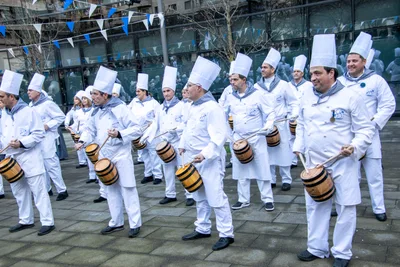 La fila de cocineros toca en la plaza, todos de blanco con el pañuelo de cuadros al cuello.