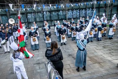 Desde arriba, la compañía toca alrededor de la ikurriña y de la bandera blanca y azul que lleva una aguadora.