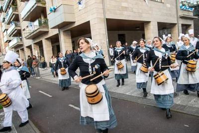 Las aguadoras desfilan por la calle tocando las barricas, entre vecinos que miran desde la acera.