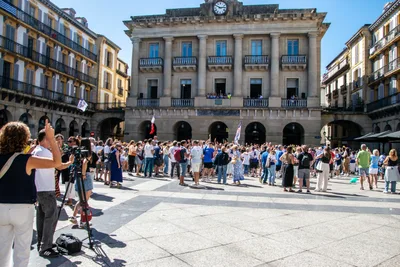 La Plaza de la Constitución llena de gente al sol, con cámaras de televisión a la izquierda y el antiguo ayuntamiento al fondo.