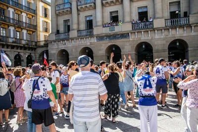 Aficionados con la camiseta blanca y azul del club levantan los brazos hacia los balcones.