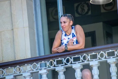 Una remera con trenzas, apoyada en la barandilla, mira hacia abajo.