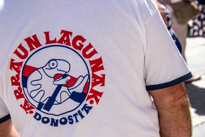 La espalda de una camiseta blanca con el escudo del club: una mano que agarra un remo dentro de un círculo.