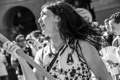 En blanco y negro, una remera sujeta el asta con el pelo al viento y mira hacia arriba.