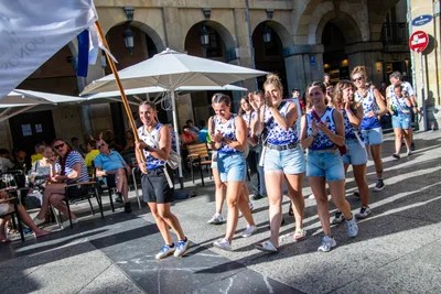 Las remeras caminan juntas por delante de las terrazas de la plaza, con la bandera.