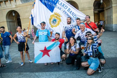Aficionados con camisetas de varios clubes posan con la bandera y una bandera gallega.