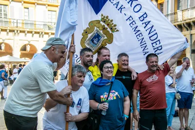 Un grupo de hombres posa abrazado bajo la Bandera de La Concha.