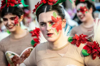 Dos mujeres con flores de pascua en el pelo y una flor roja pintada en la cara.