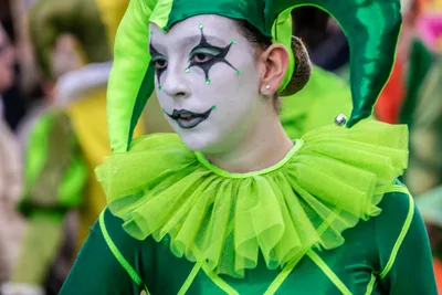 Joven con maquillaje blanco de arlequín y gorguera verde de tul.