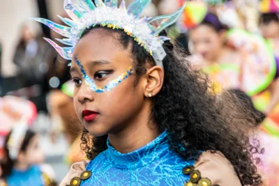 Niña con tocado de cristales y maquillaje azul, vestida de azul turquesa.