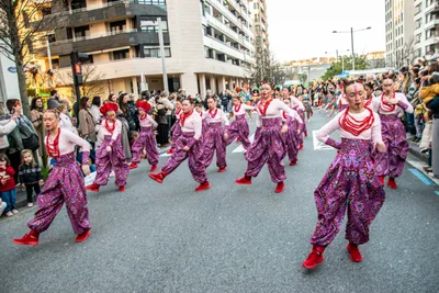 Comparsa con pantalón bombacho estampado y collares rojos, bajando la avenida.