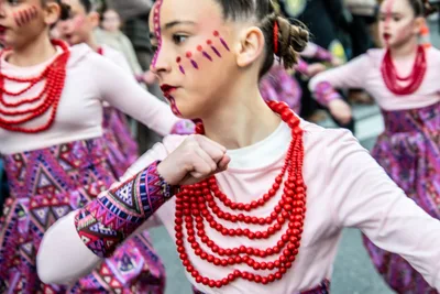 Niña con collares rojos y rayas de pintura en la cara, en pleno baile.