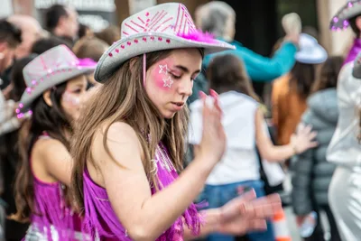 Joven con sombrero de vaquera rosa y una estrella pintada junto al ojo.