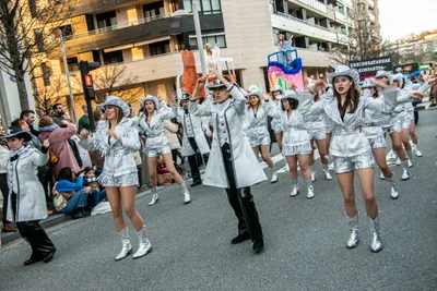 Comparsa vestida de plateado bajando la calle, con su estandarte por delante.