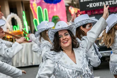 Comparsa vaquera de plateado con sombreros de estrellas, y una carroza de cactus de neón detrás.