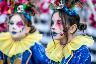 Dos niñas maquilladas de payaso, con gorguera amarilla y traje azul de lentejuelas.