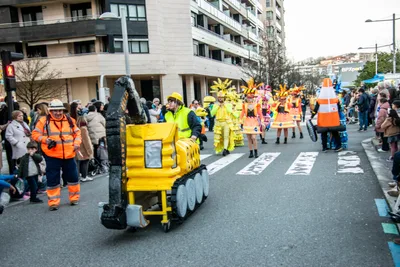 Comparsa de obras: una excavadora de cartón, conos de tráfico y chalecos reflectantes.