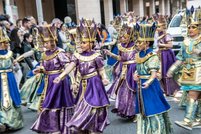Comparsa egipcia de morado y azul bailando, con los tocados en forma de corona.