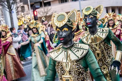 Dos figuras con tocado dorado y la cara pintada de negro, con traje verde y dorado.