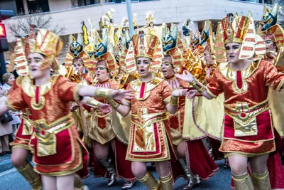 Comparsa egipcia de rojo y dorado bailando a la vez, con los tocados de faraón.