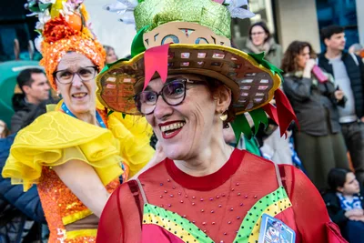 Dos mujeres con disfraz casero y sombrero de cartón, riendo entre el público.