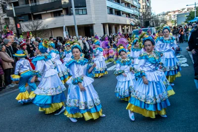 Comparsa con vestidos azules y amarillos de volantes bailando en la calle.