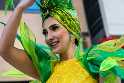 Mujer con turbante verde y vestido amarillo, con el brazo en alto.