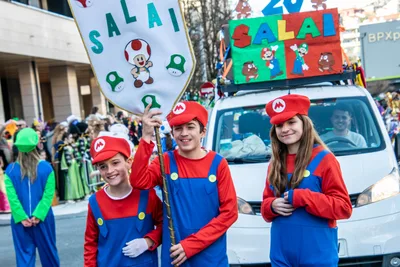Comparsa de Mario Bros con su estandarte y una furgoneta decorada detrás.