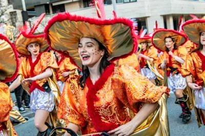 Comparsa de mosqueteros naranjas y rojos, con los sombreros de plumas.