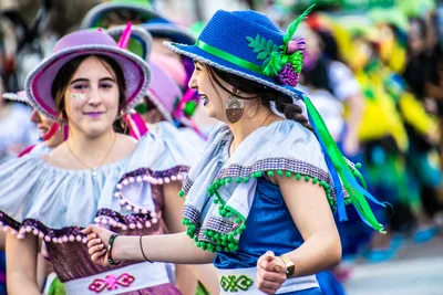 Dos jóvenes con sombrero de paja adornado y blusa blanca de volantes, con traje regional.