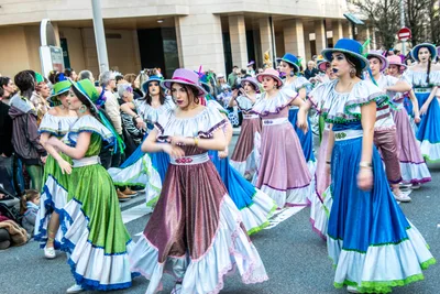 Comparsa con faldas largas de colores y blusas blancas, bailando por parejas.