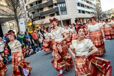 Comparsa con faldas de volantes rojas y blancas bailando por la avenida.