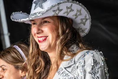 Una pregonera sonríe con un sombrero vaquero blanco cubierto de estrellas de lentejuelas.