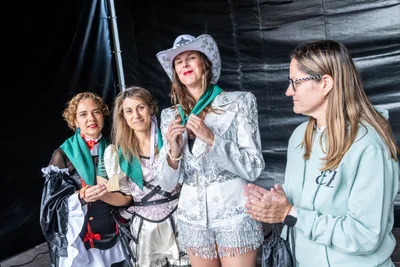 Las pregoneras con el pañuelo verde recién puesto; una lo sujeta con las dos manos y sonríe.