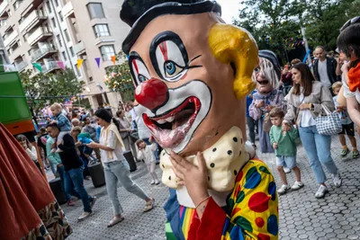 Un cabezudo de payaso, con nariz roja y pajarita de lunares, entre la gente de la kalejira.